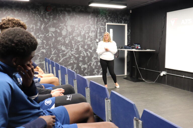 Luton Town academy players watch as Roseann Taylor from the VERU gives them a talk about knife crime